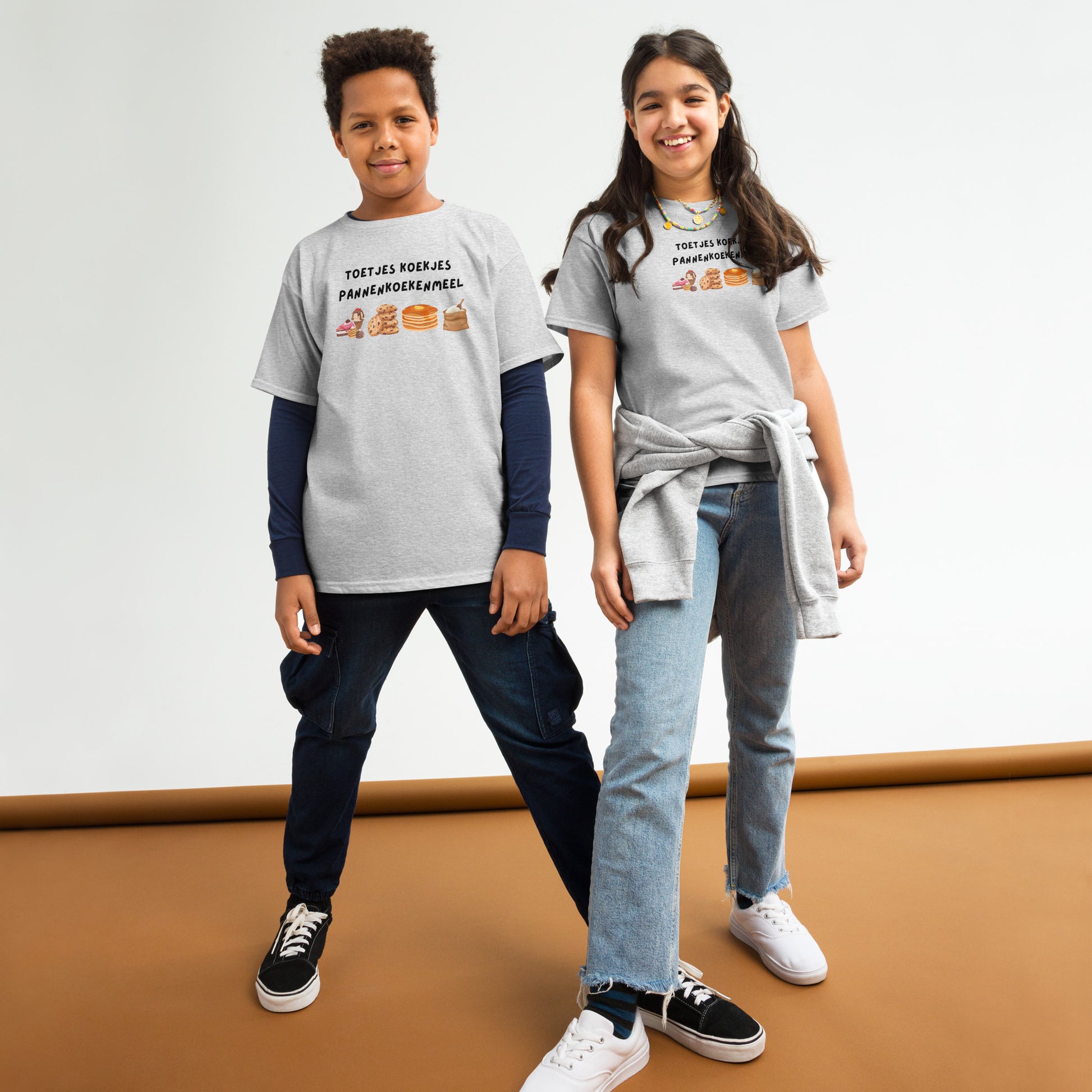 Twee kinderen dragen grappig kinder t-shirt eten met tekeningen van koekjes en paasbrood op grijze achtergrond