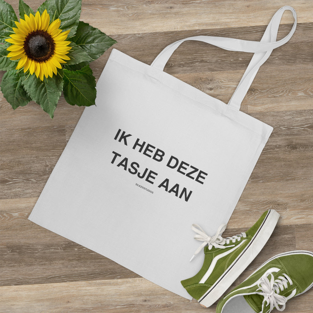 Witte tote bag met tekst ik heb deze tasjes aan tote bag naast groene schoenen en zonnebloem