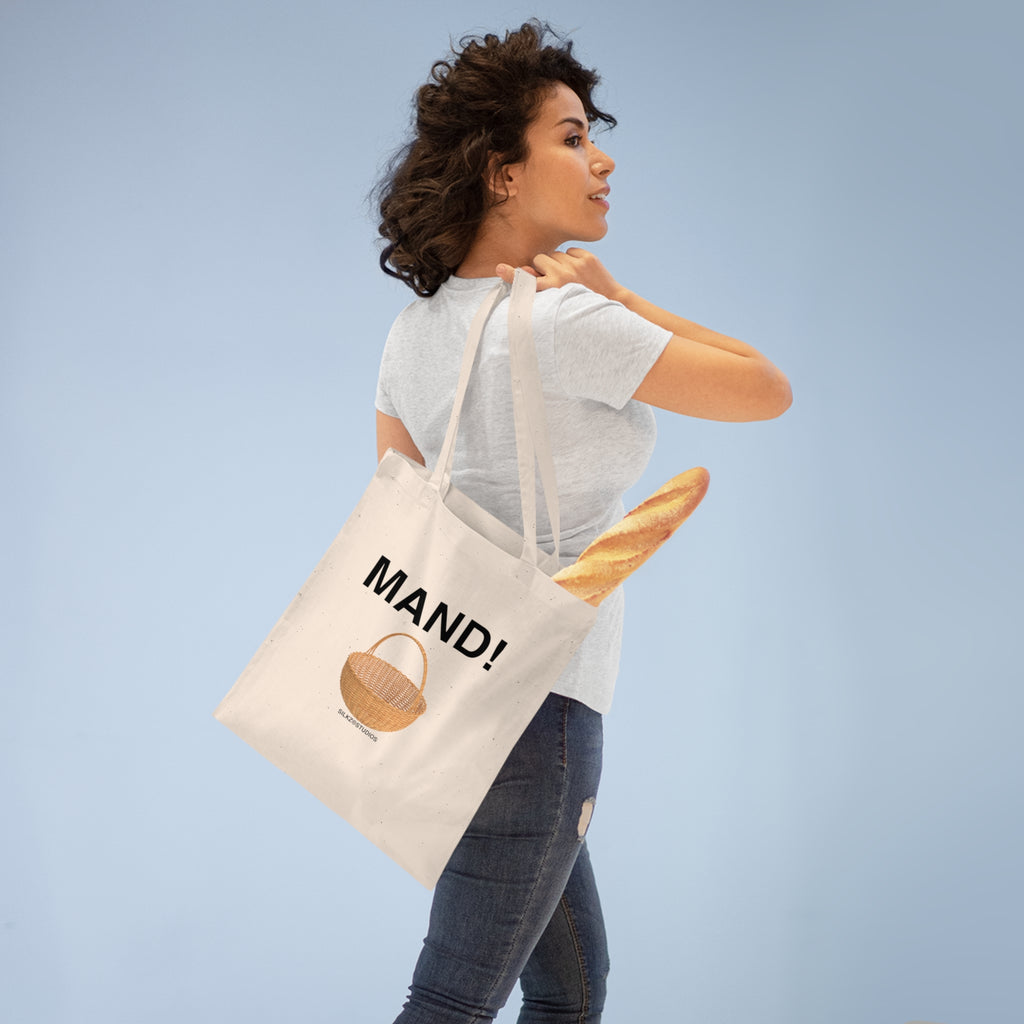 Vrouw draagt een Printify MAND tote bag met een stokbrood erin tegen een blauwe achtergrond