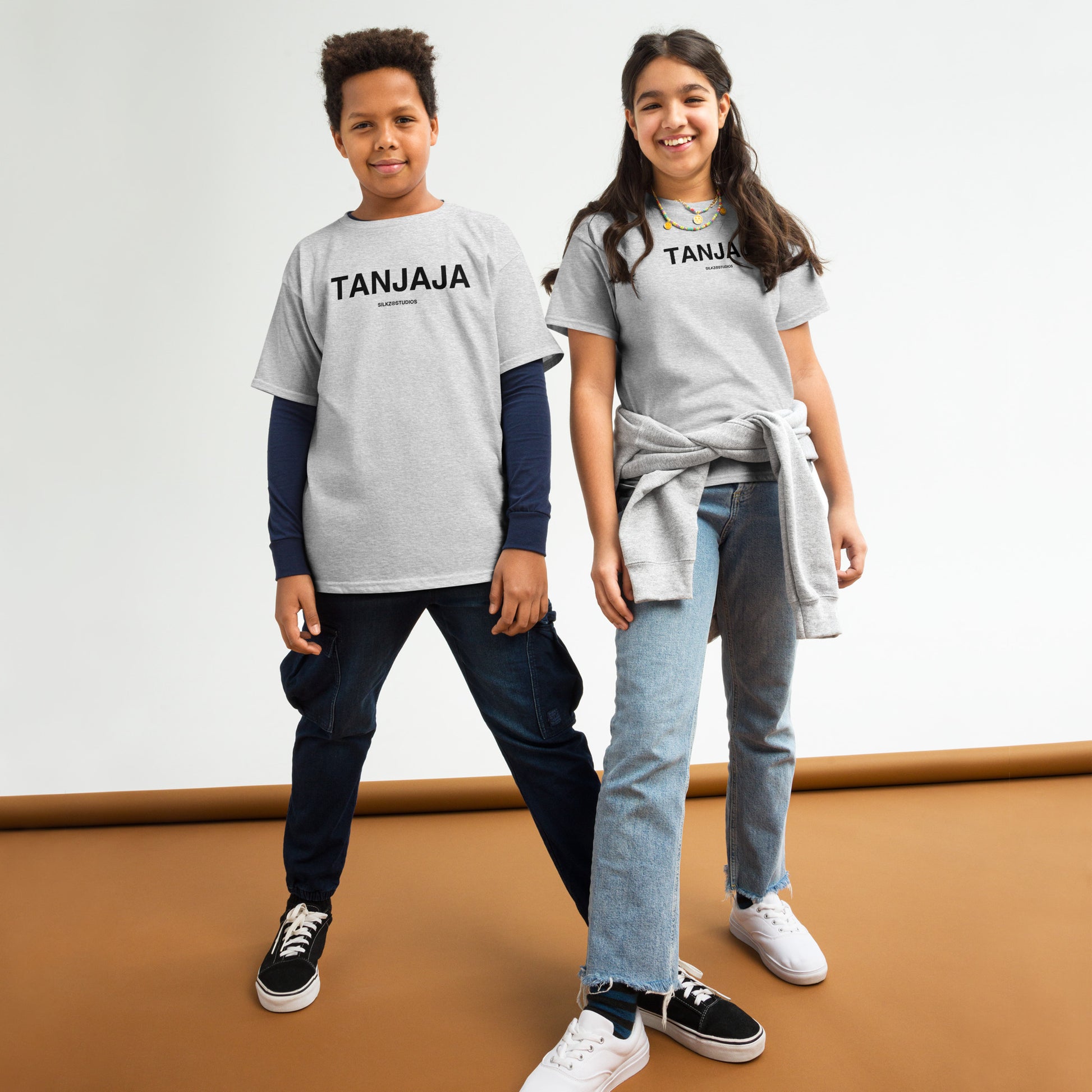 Twee kinderen dragen een grijs kindertshirt met opdruk TANJAJA van SILKZ STUDIOS in een studio