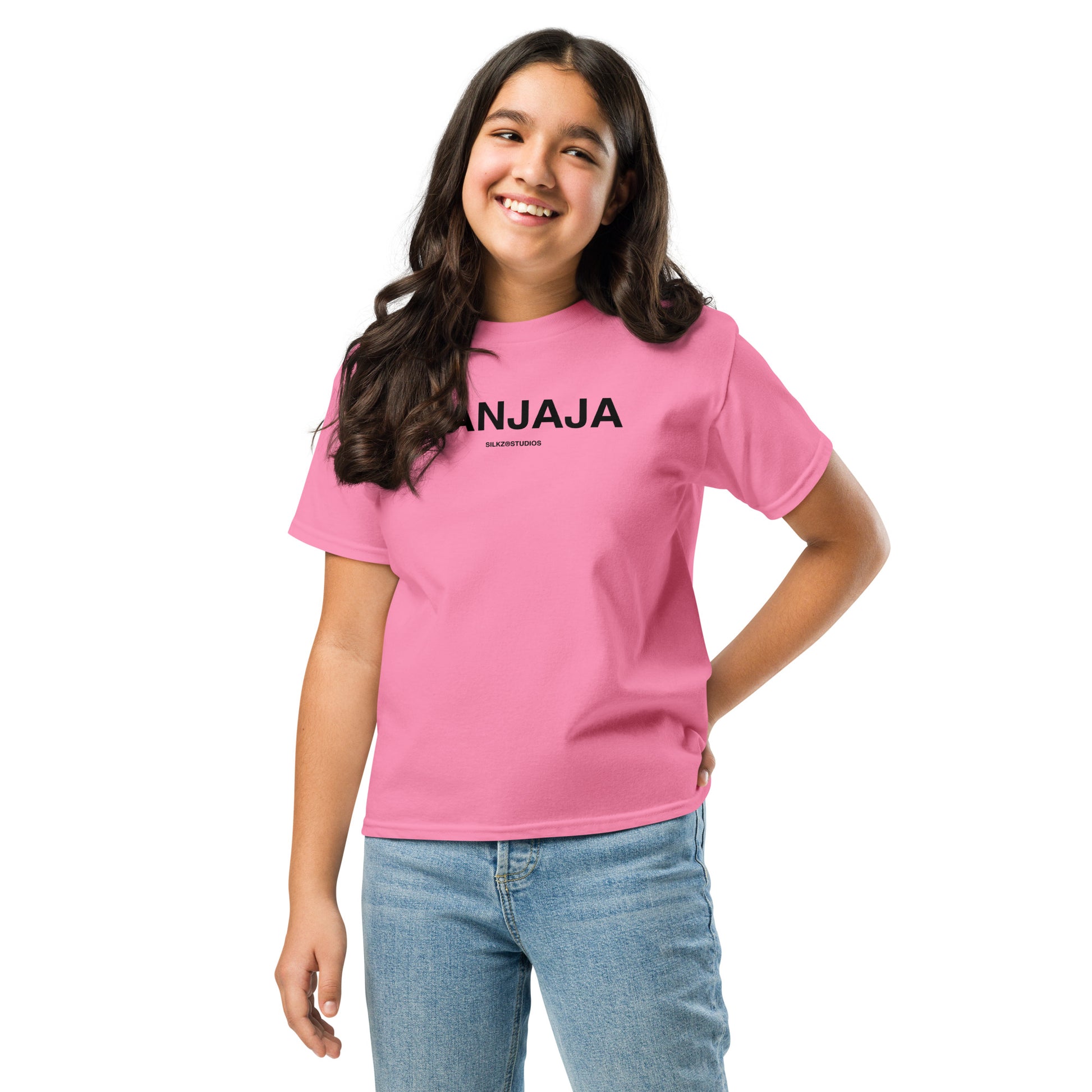 Meisje draagt roze kindertshirt met opdruk ANJAJA en blauwe spijkerbroek lachend